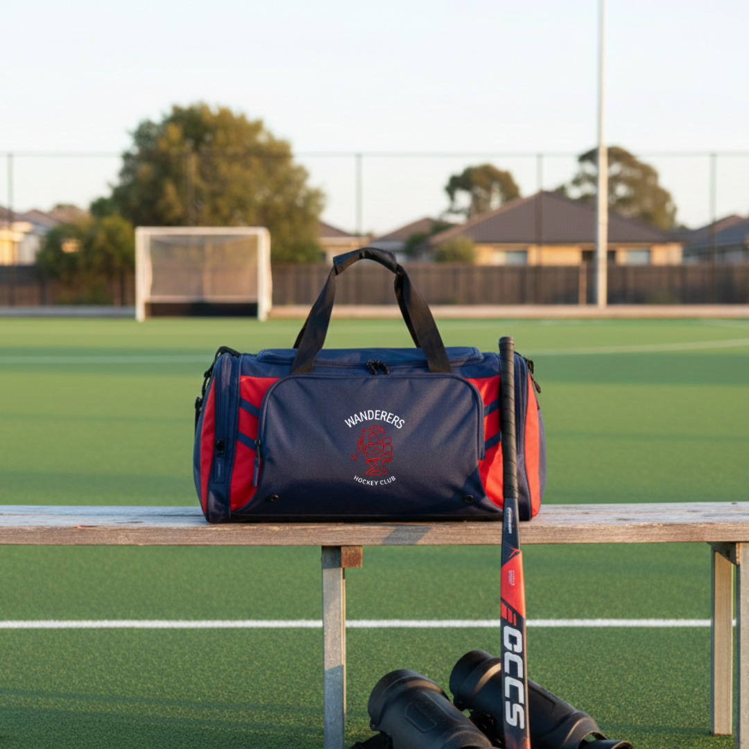 Navy and red sports bag with 'Wanderers Hockey Club' branding on a wooden bench in a hockey field.