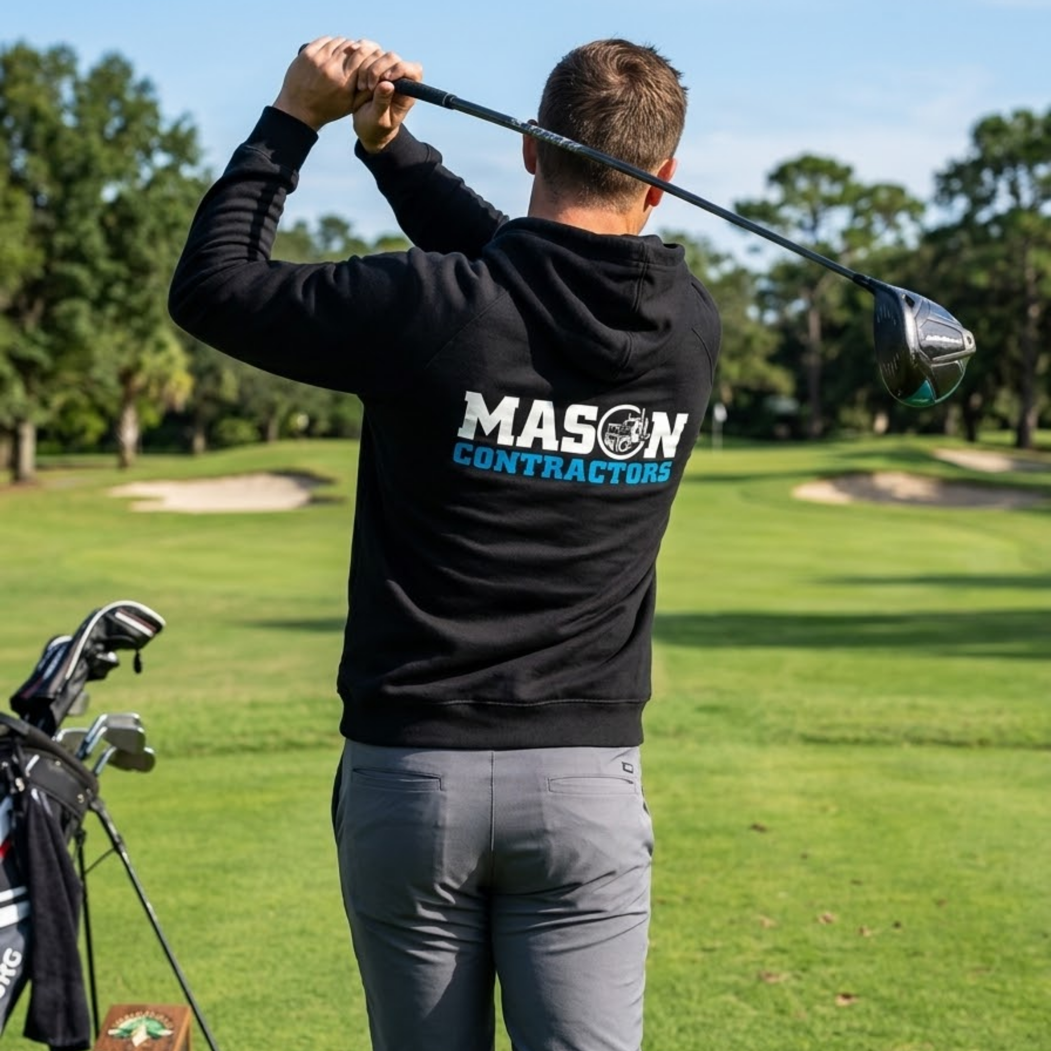 Person on a golf course wearing a black hoodie with 'Mason Contractors' branding.