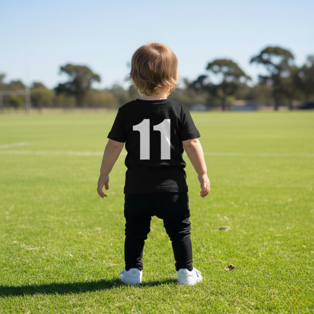 Child wearing a black shirt with the number 11 on a grassy field