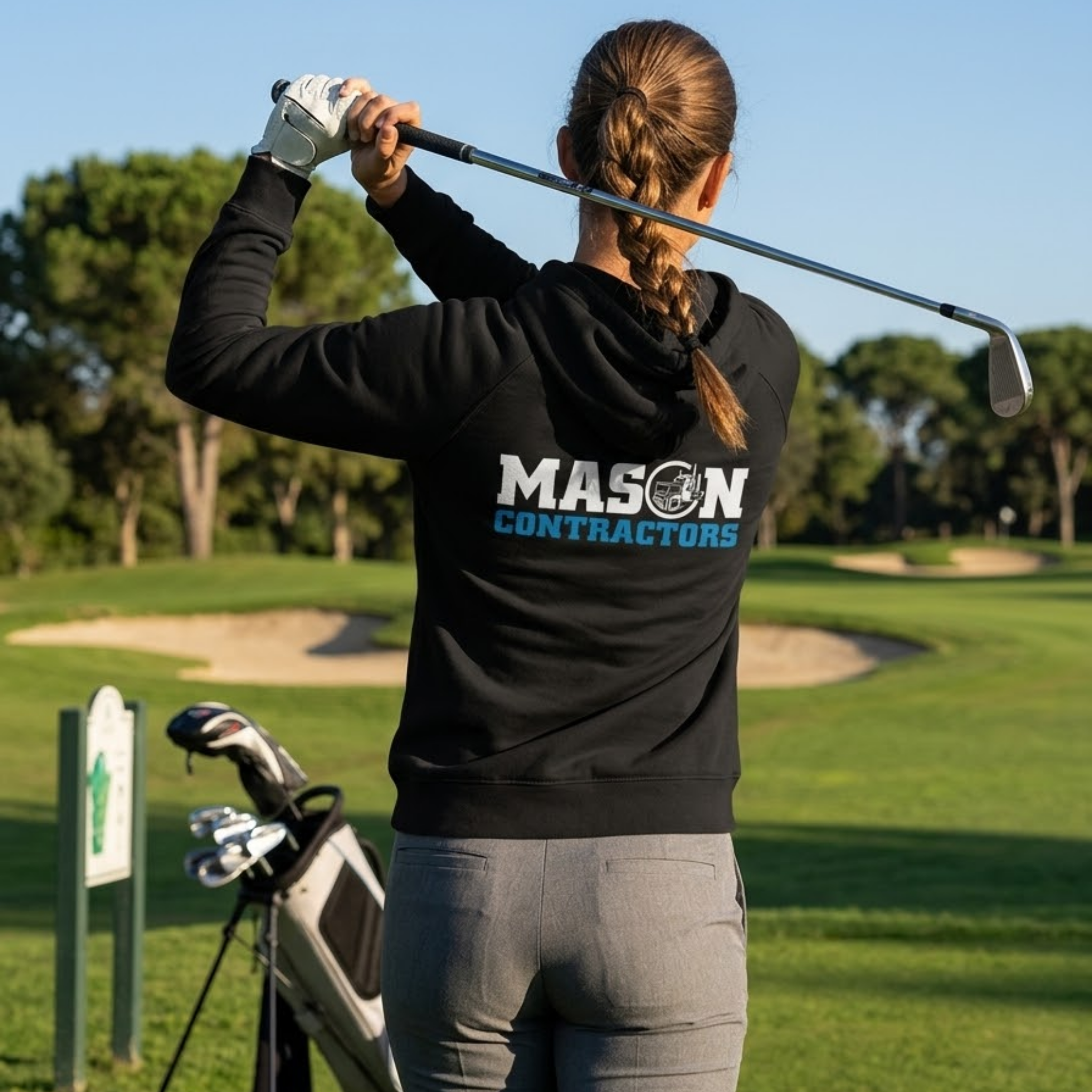 Person in a black hoodie with 'Mason Contractors' logo on a golf course