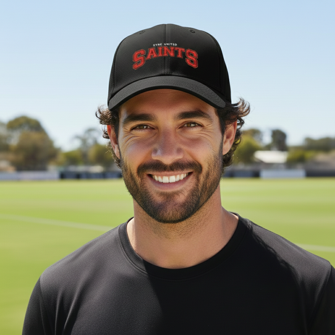 Man wearing SAINTS embroidered cap on a football oval on a sunny day