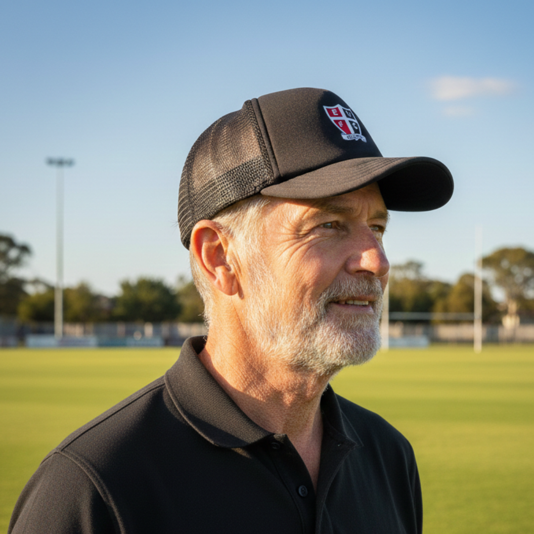 Man on a football oval wearing a saints shield logo trucker cap