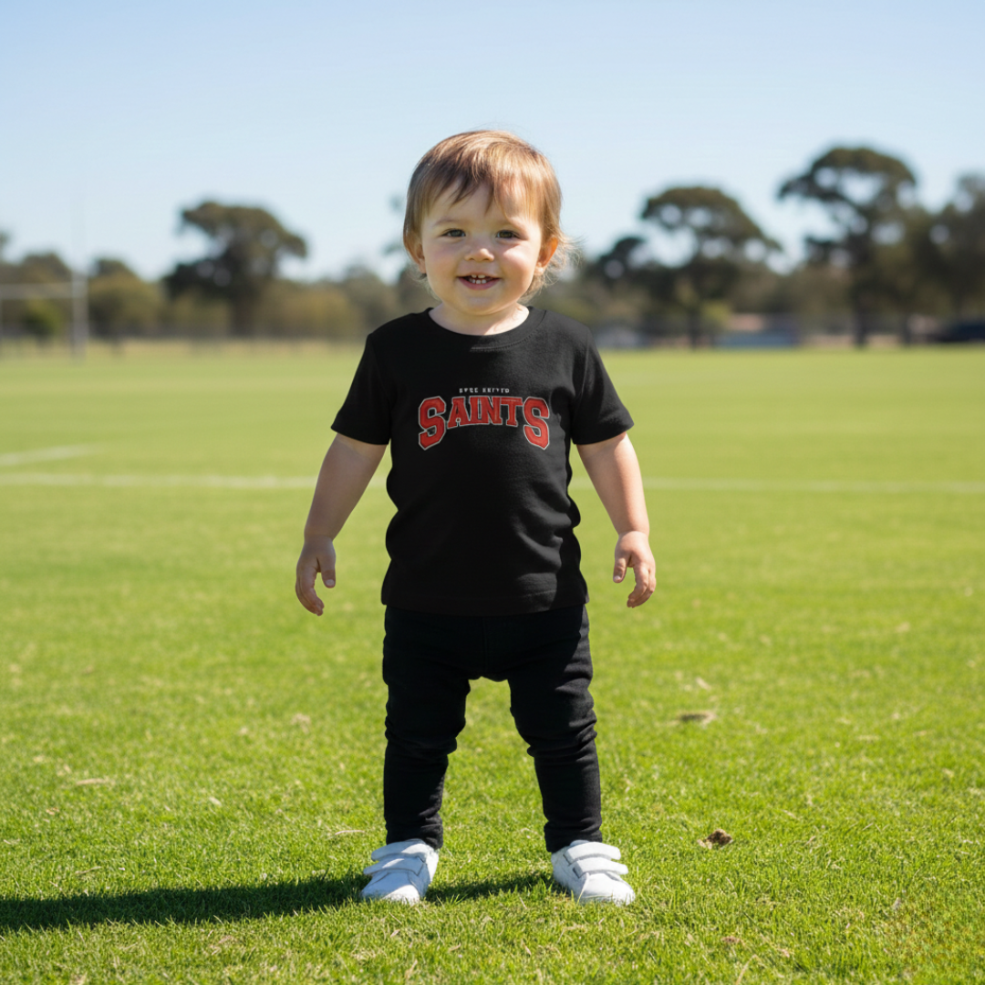 Child wearing a black t-shirt with red text on a grassy field