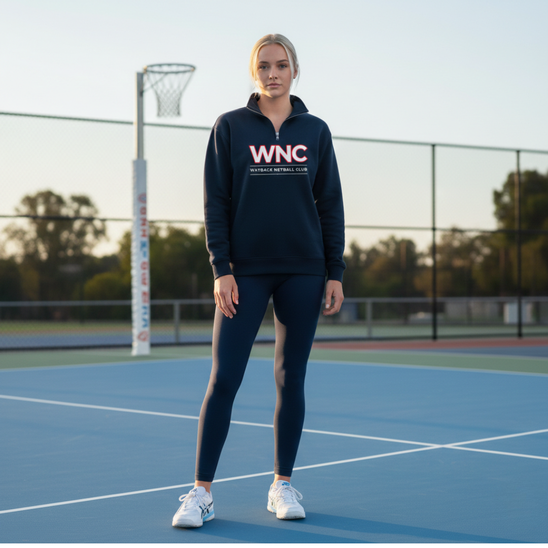 Person wearing a navy quarter zip with 'WNC' on a netball court