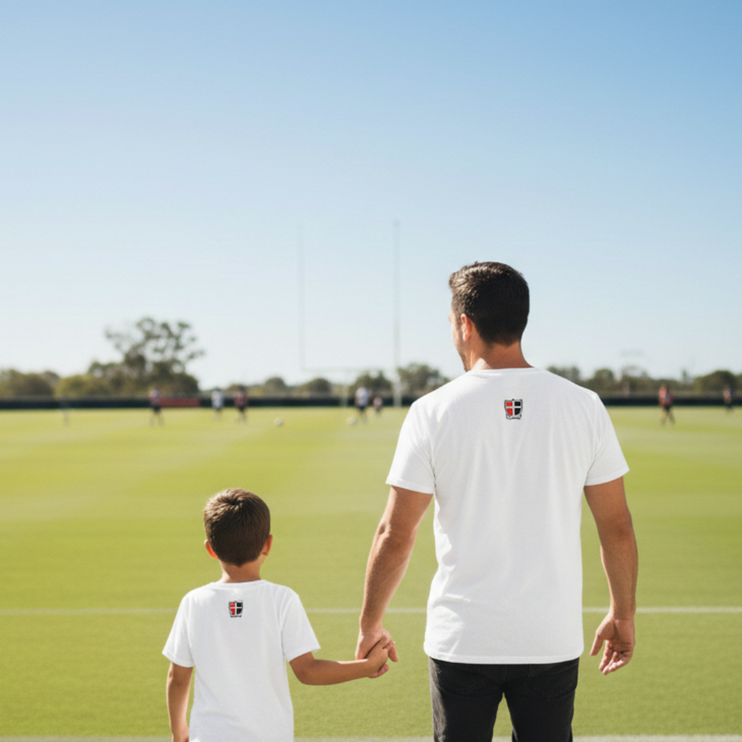Man and child holding hands on a sports field with clear blue sky