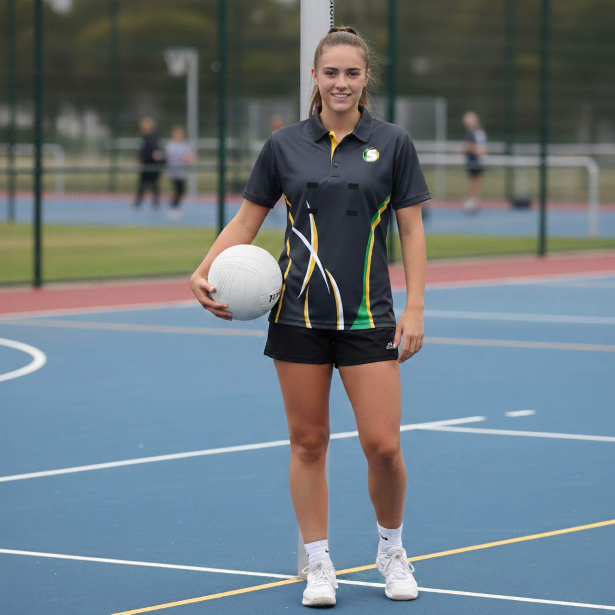 Person holding a netball on an outdoor court