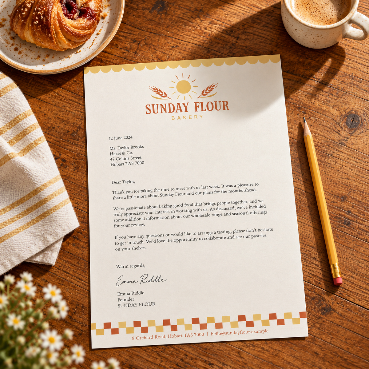 Cream Sunday Flour Bakery letterhead with terracotta and yellow details, shown on a timber table beside a pastry, coffee and pencil.