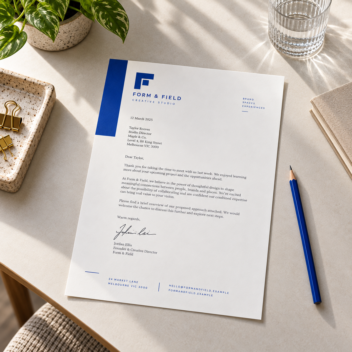 Blue and white Form & Field letterhead on a light desk, with a sample letter, plant, glass and blue pencil.