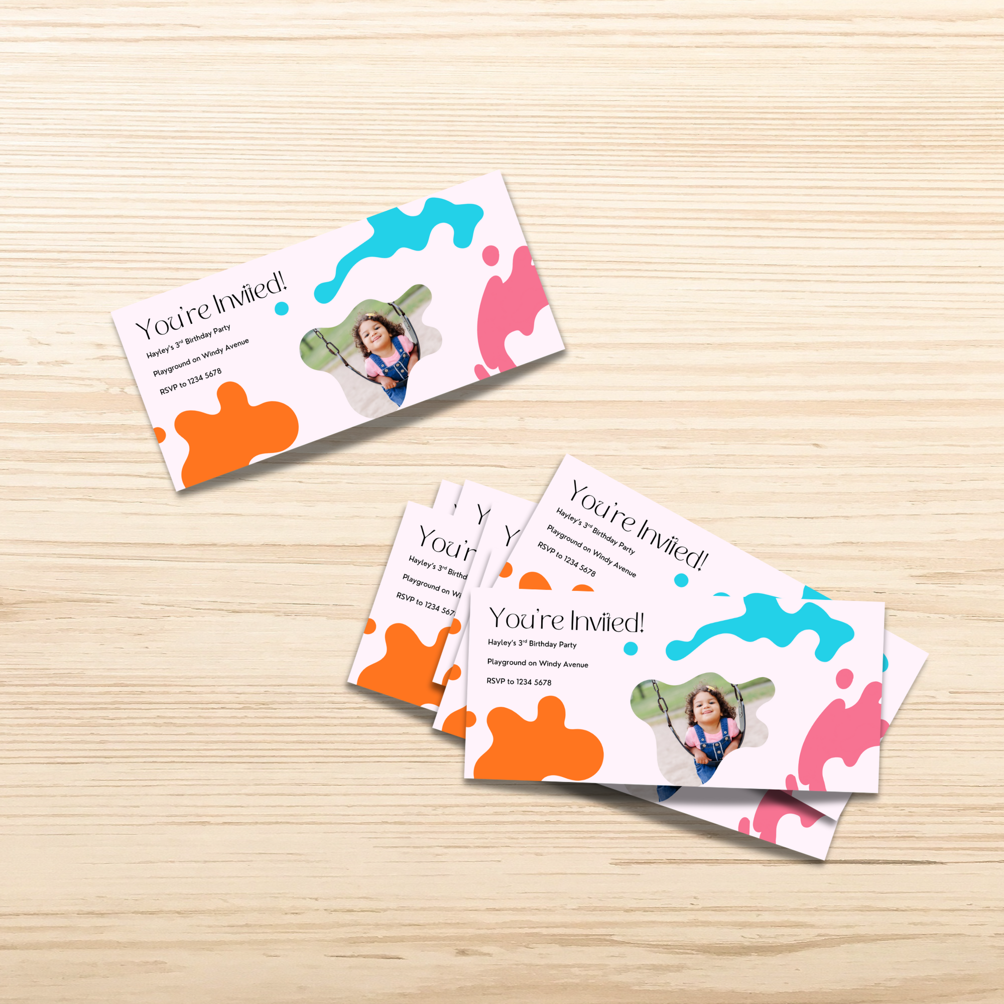 Colorful DL flyer invitation cards with abstract designs on a wooden surface